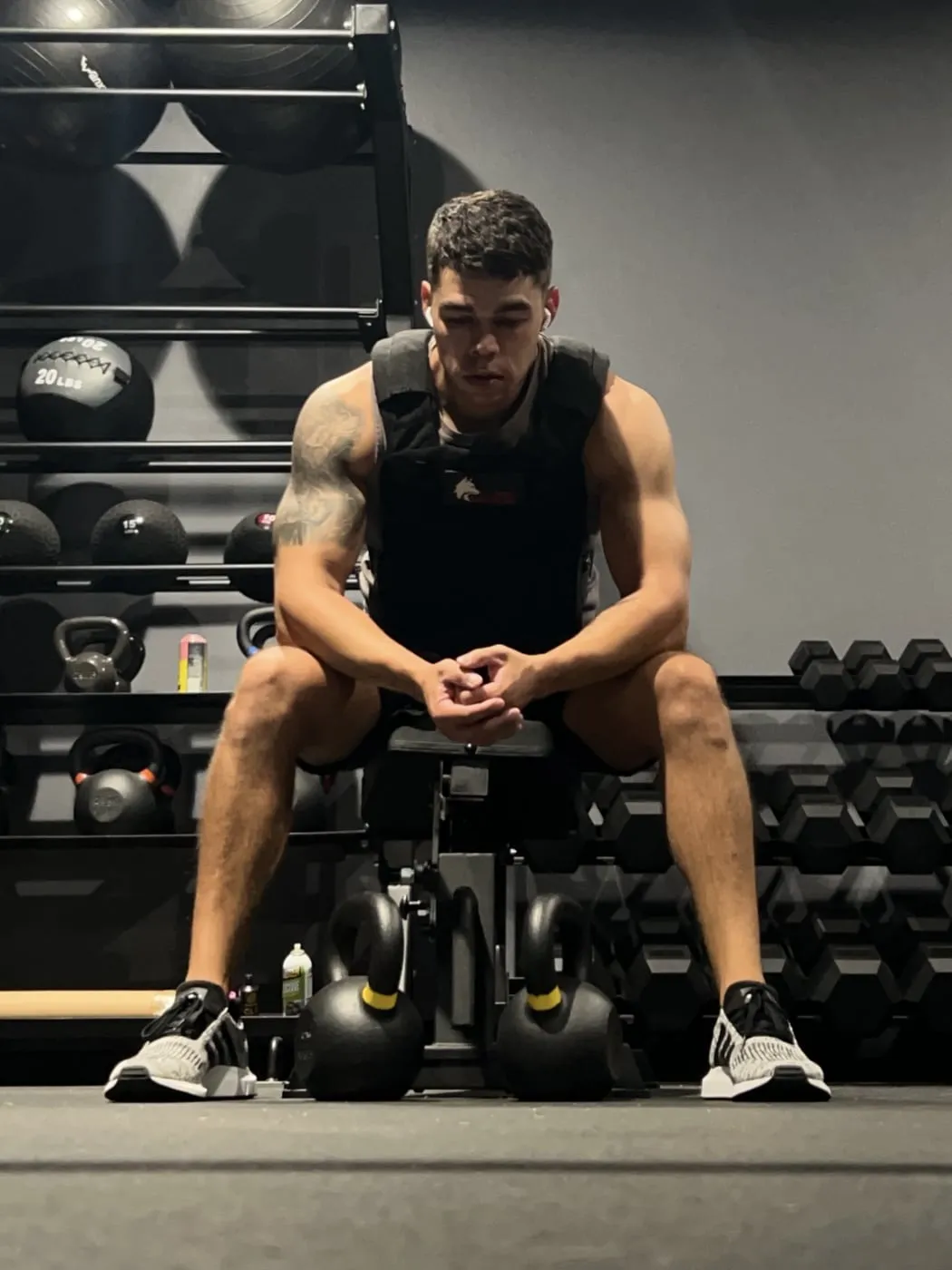 Austin, owner and personal trainer at Iron Ambition Training, seated on a bench on the studio floor