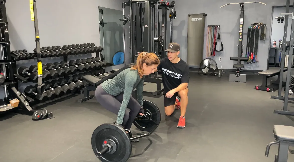 Austin coaching a client through a deadlift set-up on the studio floor